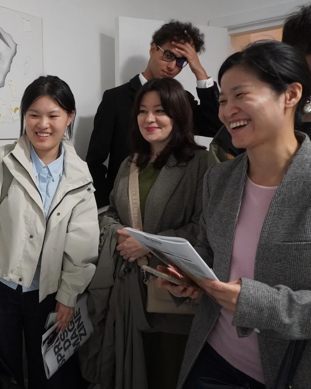Gallery visitors smiling together, with a SPREADS cover visible at left.