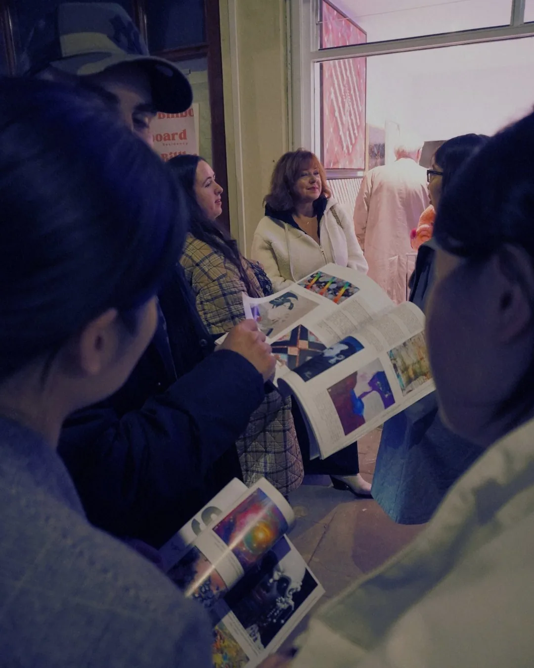 Visitors looking through open art magazines together.